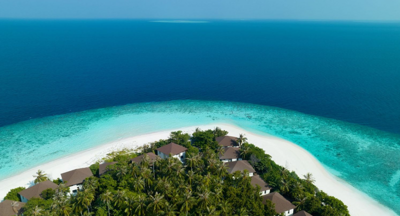 The east tip of the island at Avani+ Fares Maldives from the air, beachside rooms among the trees and a turquoise lagoon.