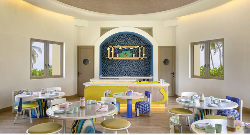 Petit Bistro, the children's restaurant at Avani+ Fares Maldives, with small tables and a blue arched counter.