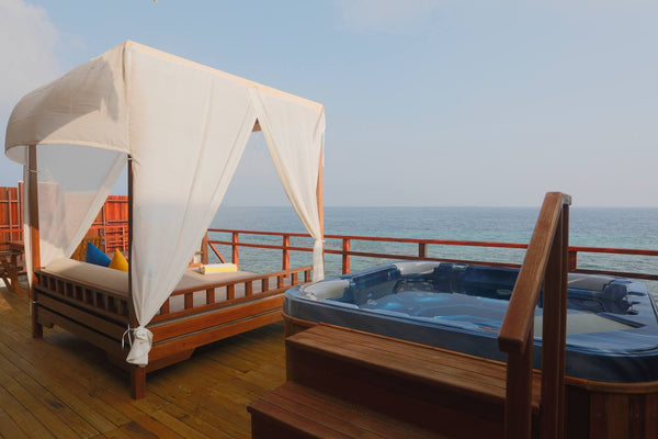 Curtained daybed on a villa deck looking out over the sea at Furaveri Maldives