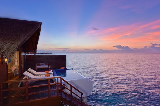 A Pool Water Villa at Grand Park Kodhipparu at sunset, its pool and loungers facing the sea