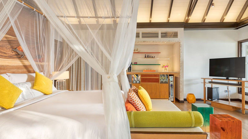 The bedroom of an Earth Villa with Pool at OZEN LIFE Maadhoo, a four poster bed under a mosquito net beside a green daybed