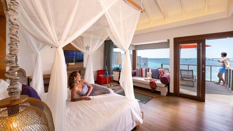 OBLU SELECT Sangeli, North Malé Atoll: a canopy bed in an overwater villa, the deck and sea through open doors