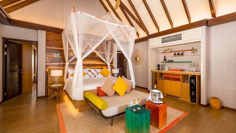 The bedroom of an Earth Villa at OZEN LIFE Maadhoo, a four poster bed under a mosquito net with a timber ceiling above