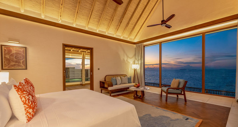 A bedroom looking out to sea at dusk at RAH GILI Maldives.