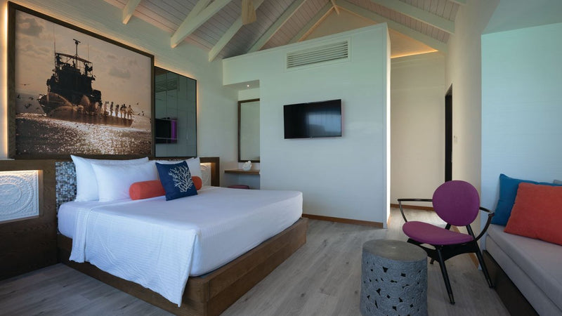 OBLU Xperience Ailafushi, North Malé Atoll: a Water Villa bedroom and seating corner