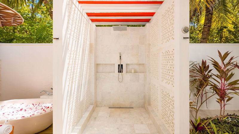 The garden bathroom of an Earth Villa at OZEN LIFE Maadhoo, a rain shower in a coral stone room open to the sky