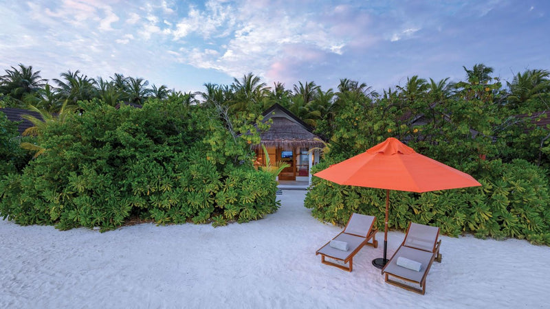 OBLU SELECT Sangeli, North Malé Atoll: a beach villa behind the vegetation, loungers and an umbrella on the sand in front