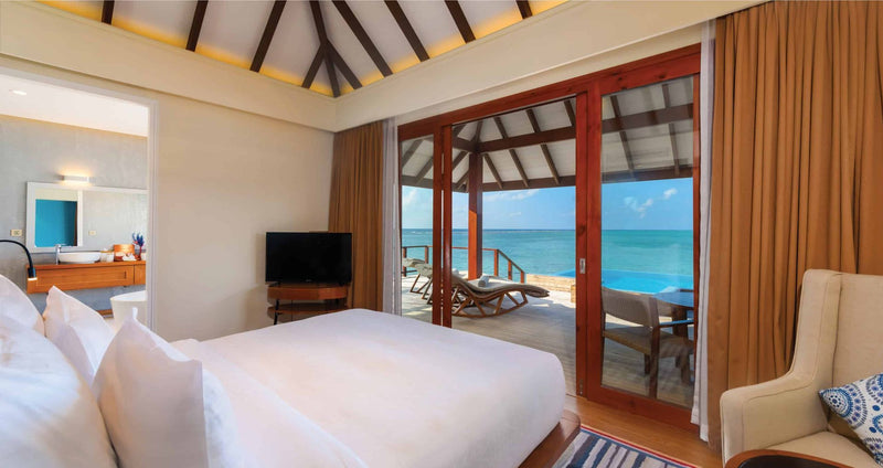 VARU by Atmosphere, North Malé Atoll: a water villa bedroom opening onto the deck and the sea