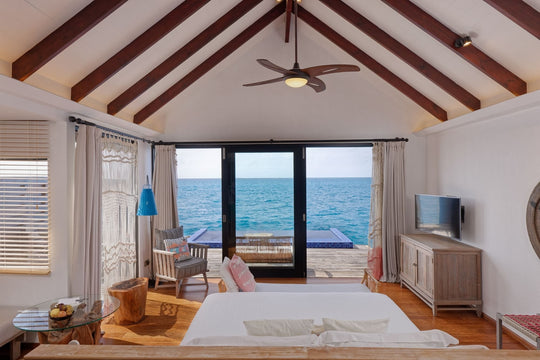 A Reef Pool Water Villa bedroom at Grand Park Kodhipparu, a timber ceiling above and the ocean in view