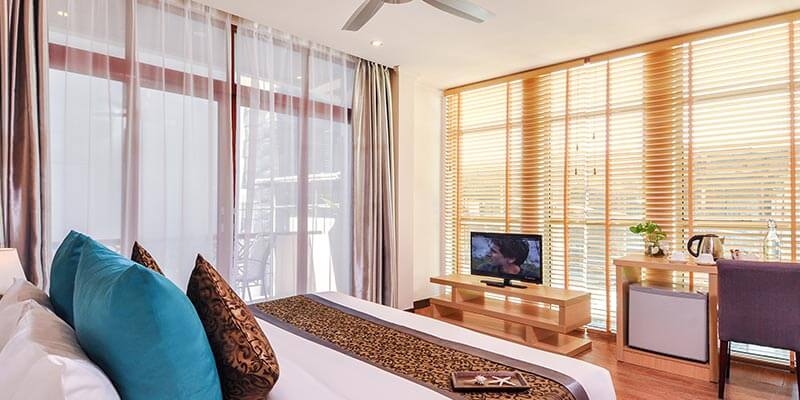 Triple room at Triton Beach Hotel with a double and a single bed and balcony doors