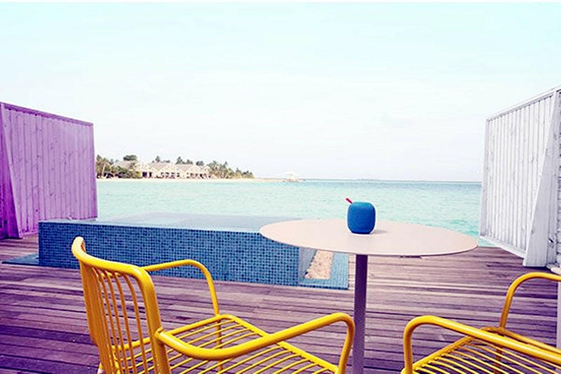 A water villa deck at The Standard Huruvalhi, yellow chairs and a round table by the pool edge.