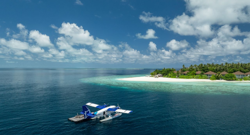 A seaplane at the floating platform of Avani+ Fares Maldives, the island on the horizon.