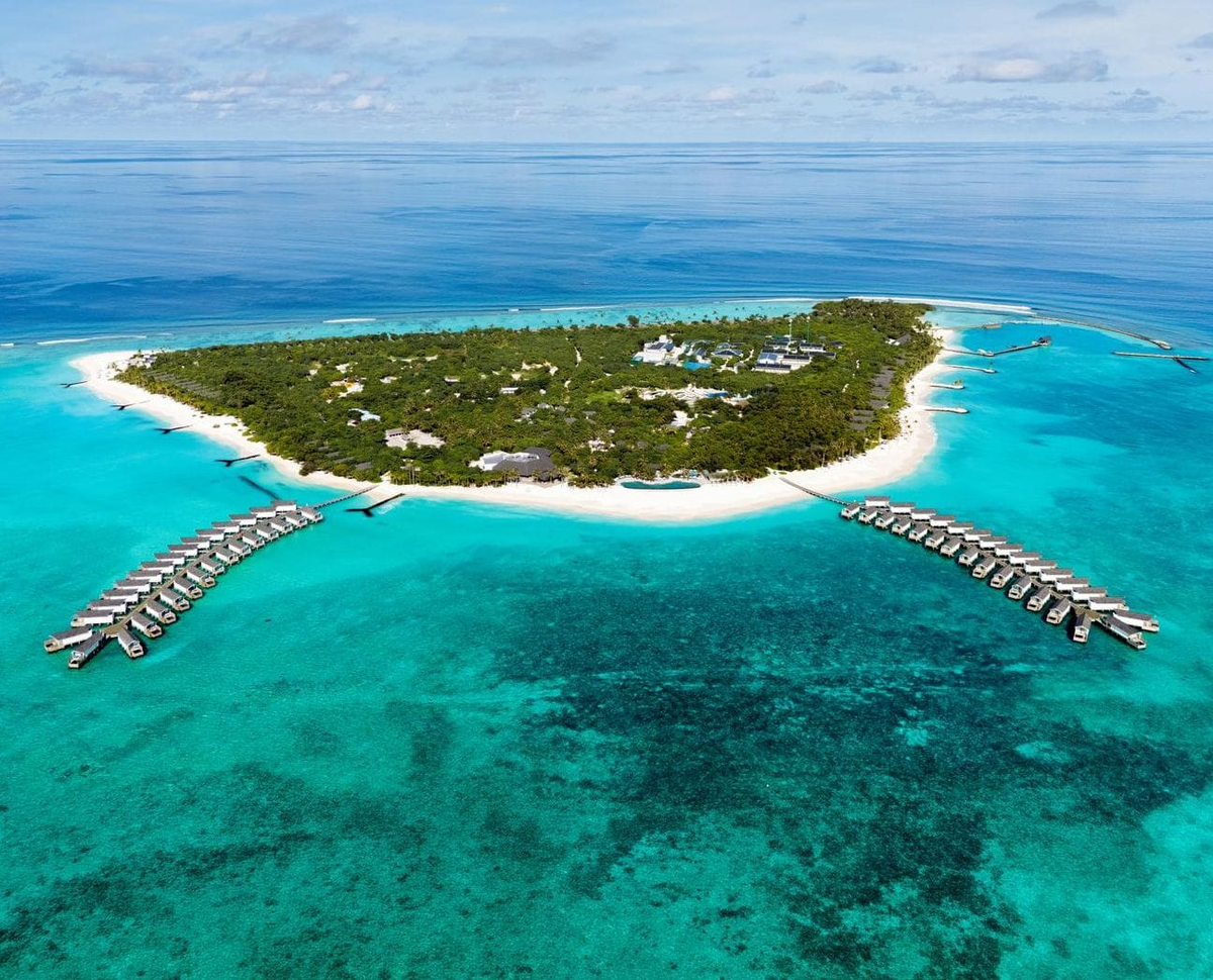 RAAYA by Atmosphere, Raa Atoll: the island from the air, with a water villa jetty on either side