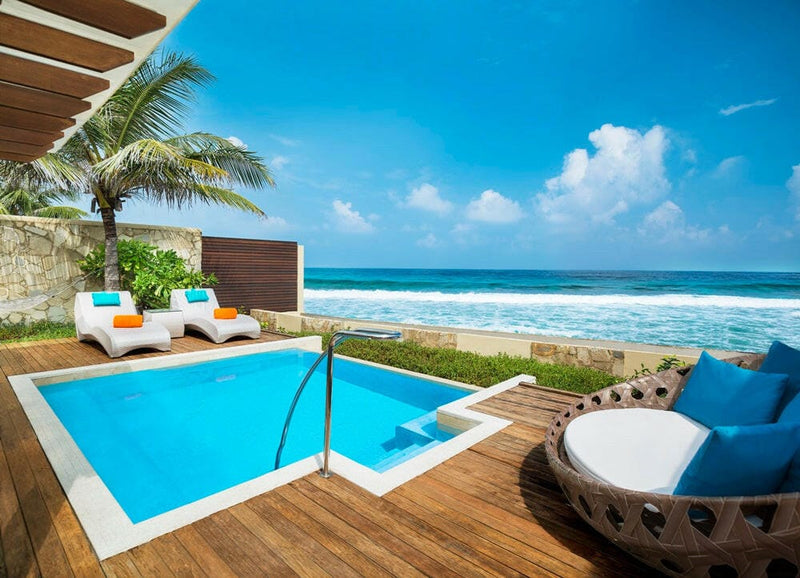 A villa pool at Sheraton Maldives Full Moon, a round rattan daybed on the deck above the breaking reef.