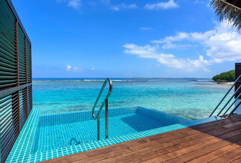 A villa plunge pool at Sheraton Maldives Full Moon, blue mosaic tiles and a handrail on an overwater deck.