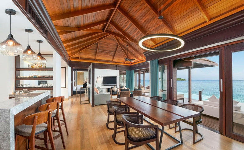 A two bedroom villa at Sheraton Maldives Full Moon, a long dining table and bar stools under a timber ceiling.