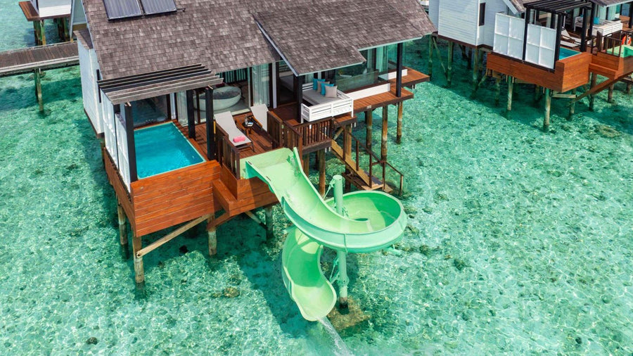 A Wind Villa with Jacuzzi & Slide at OZEN LIFE Maadhoo from above, its jacuzzi and green slide running into the shallows