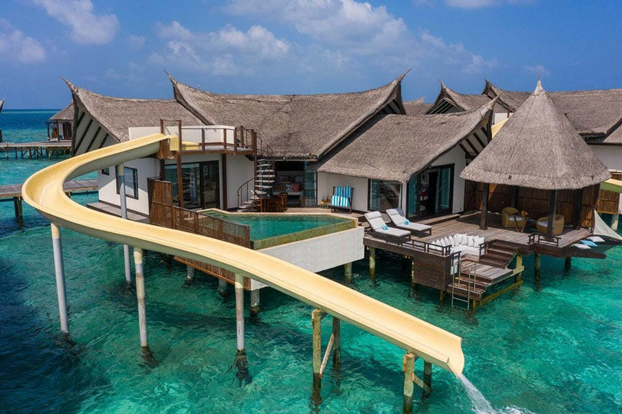 An Ocean Pool Suite with Slide at OZEN Reserve Bolifushi from the air, its slide sweeping into the turquoise water
