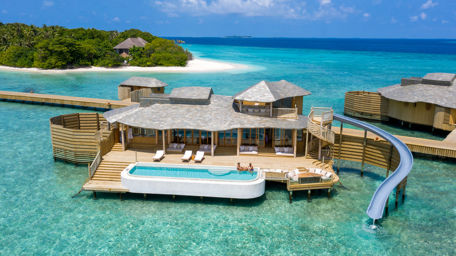 An overwater villa at Soneva Fushi with a private pool and a slide into the lagoon