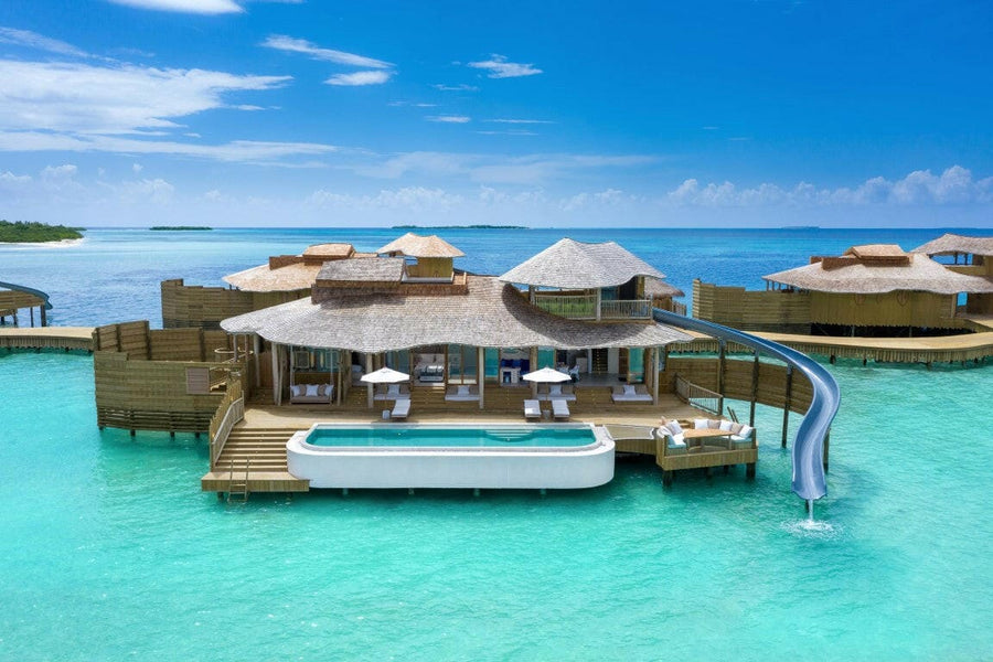 A 1 Bedroom Water Reserve with Slide at Soneva Jani seen from the lagoon, a white slide curving down past the pool deck