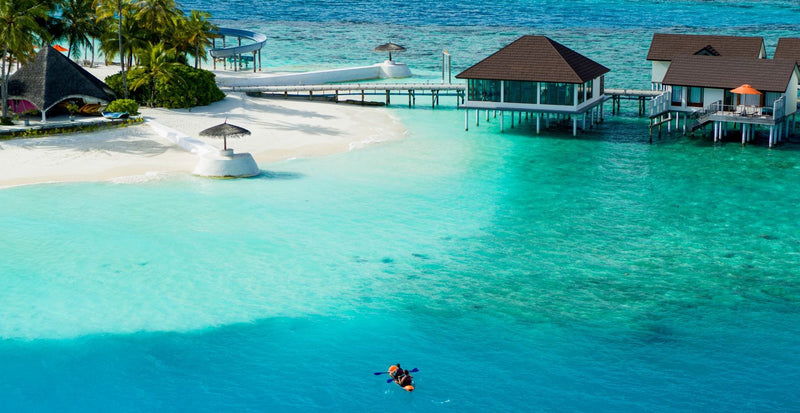 OBLU SELECT Sangeli, North Malé Atoll: a snorkeller in the shallow lagoon beside the overwater villas