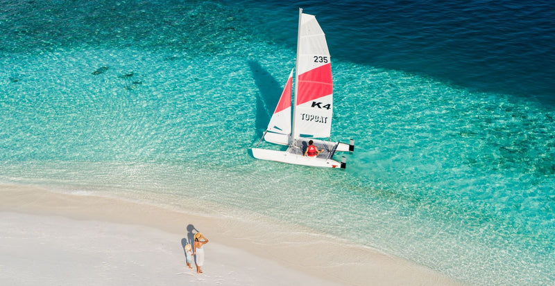 OBLU SELECT Sangeli, North Malé Atoll: a catamaran sailing in the shallows just off the beach
