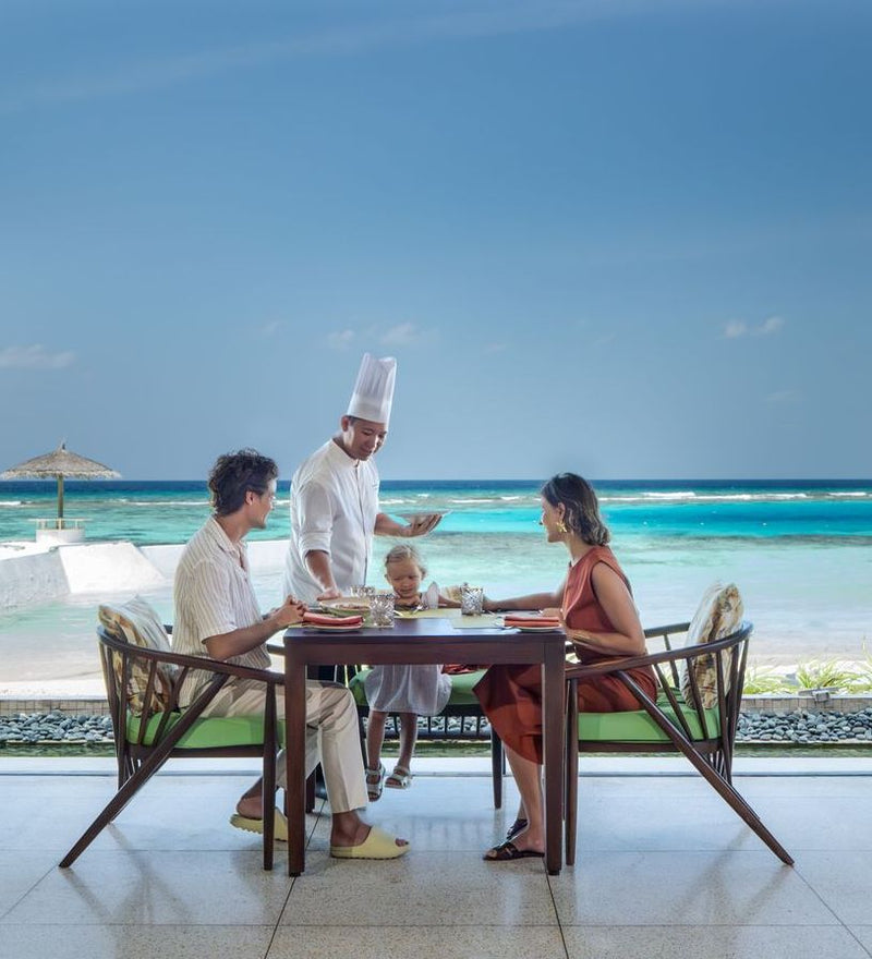 OBLU SELECT Sangeli, North Malé Atoll: a chef serving a family at a table on the beach