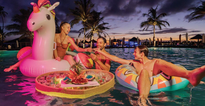 OBLU Xperience Ailafushi, North Malé Atoll: guests on inflatables in the pool at dusk