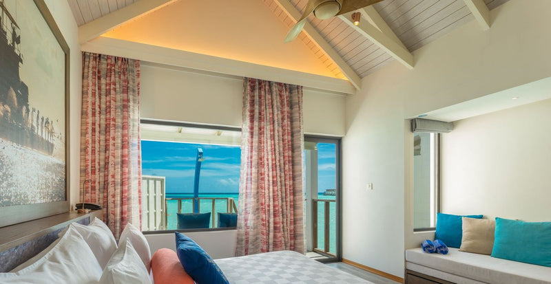 OBLU Xperience Ailafushi, North Malé Atoll: a bedroom with a sloped ceiling and a window onto the lagoon