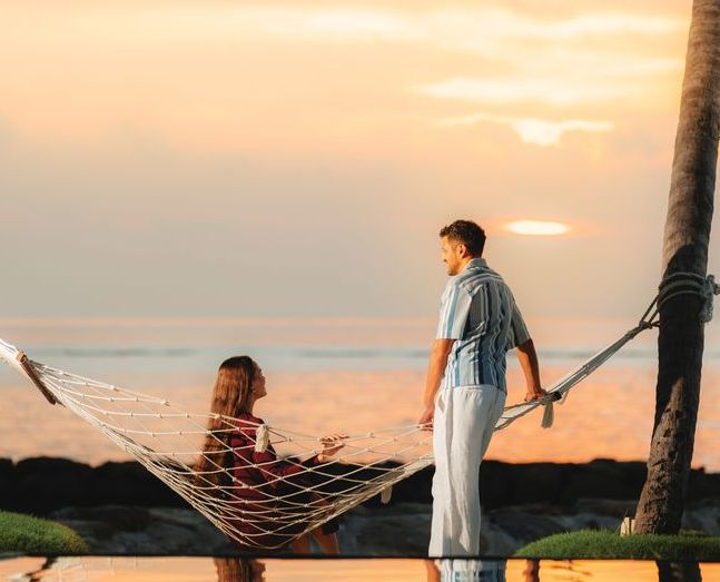 VARU by Atmosphere, North Malé Atoll: a couple by a hammock on the beach at sunset