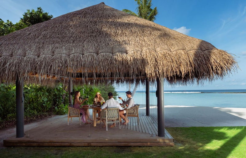RAAYA by Atmosphere, Raa Atoll: guests at lunch under a thatched beach pavilion