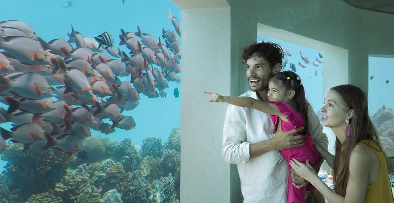 OBLU Xperience Ailafushi, North Malé Atoll: a family watching fish through the glass at the underwater restaurant