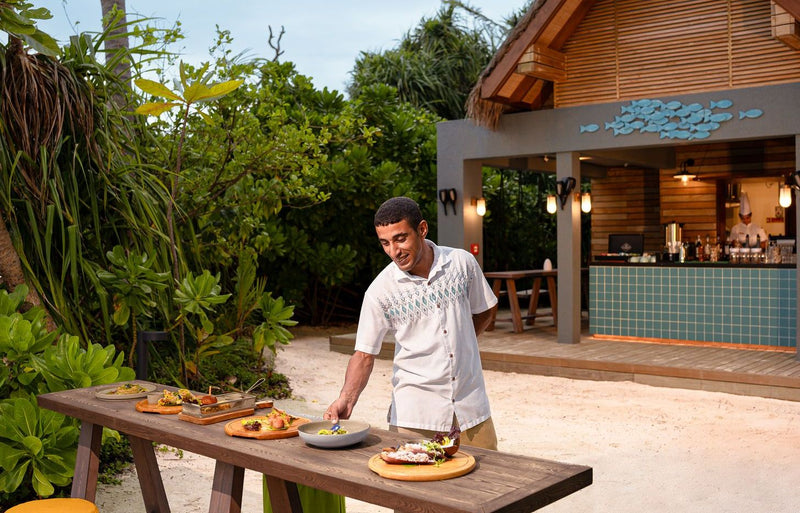 RAAYA by Atmosphere, Raa Atoll: a chef laying out snacks at a beach bar
