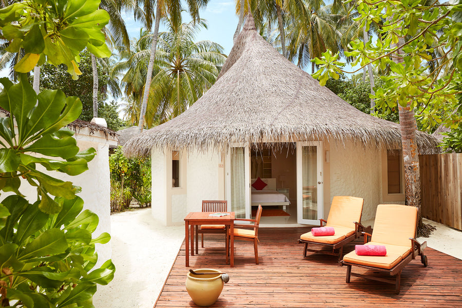 A thatched Beach Villa with Pool at Sun Siyam Vilu Reef, its terrace and sunloungers under the palms