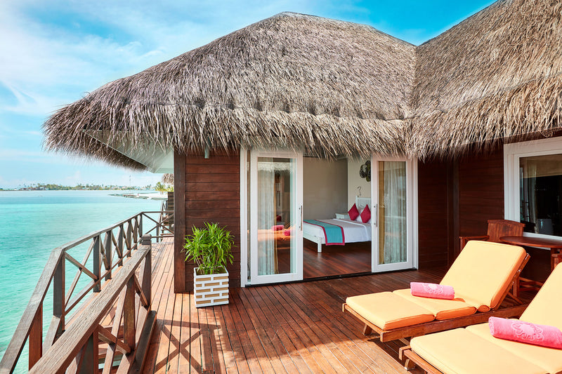 The deck of a Reef Villa at Sun Siyam Vilu Reef, sunloungers facing the lagoon and the bedroom behind