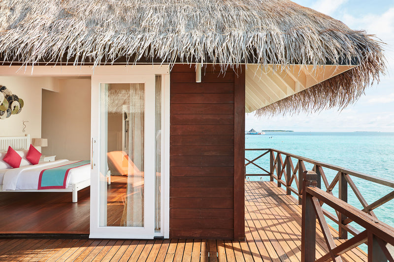 A Sunset Reef Villa at Sun Siyam Vilu Reef, the bedroom opening onto a deck over the lagoon
