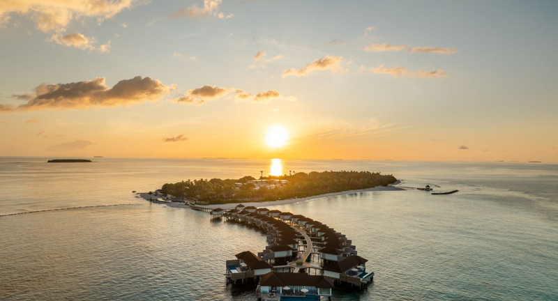 Sunrise over Avani+ Fares Maldives, with the overwater villa jetty in the foreground.