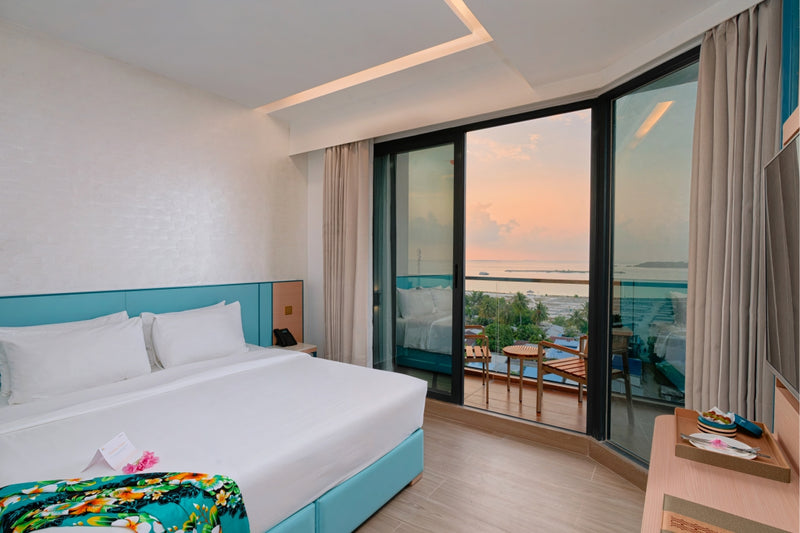 h78 Guraidhoo, South Malé Atoll: a Sunset Island Prime room with a double bed beside tall windows