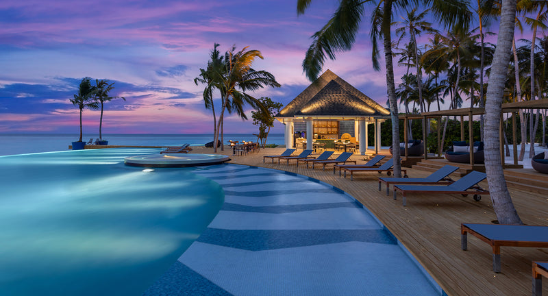 The pool and Skipjack poolside bar at Avani+ Fares Maldives, lit up at dusk.