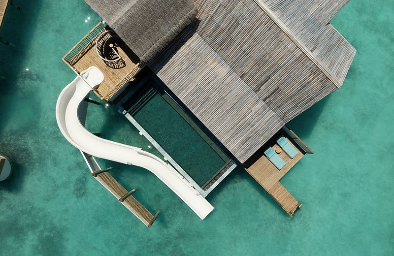 An overwater villa with a water slide at RAH GILI Maldives from the air.
