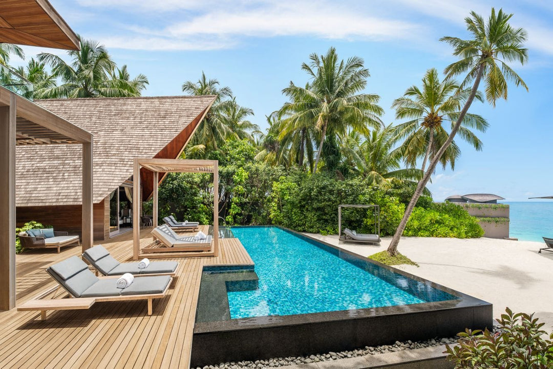 The St. Regis Maldives Vommuli, Dhaalu Atoll — Villa deck with loungers, a shaded pavilion and a pool, palms and sea beyond
