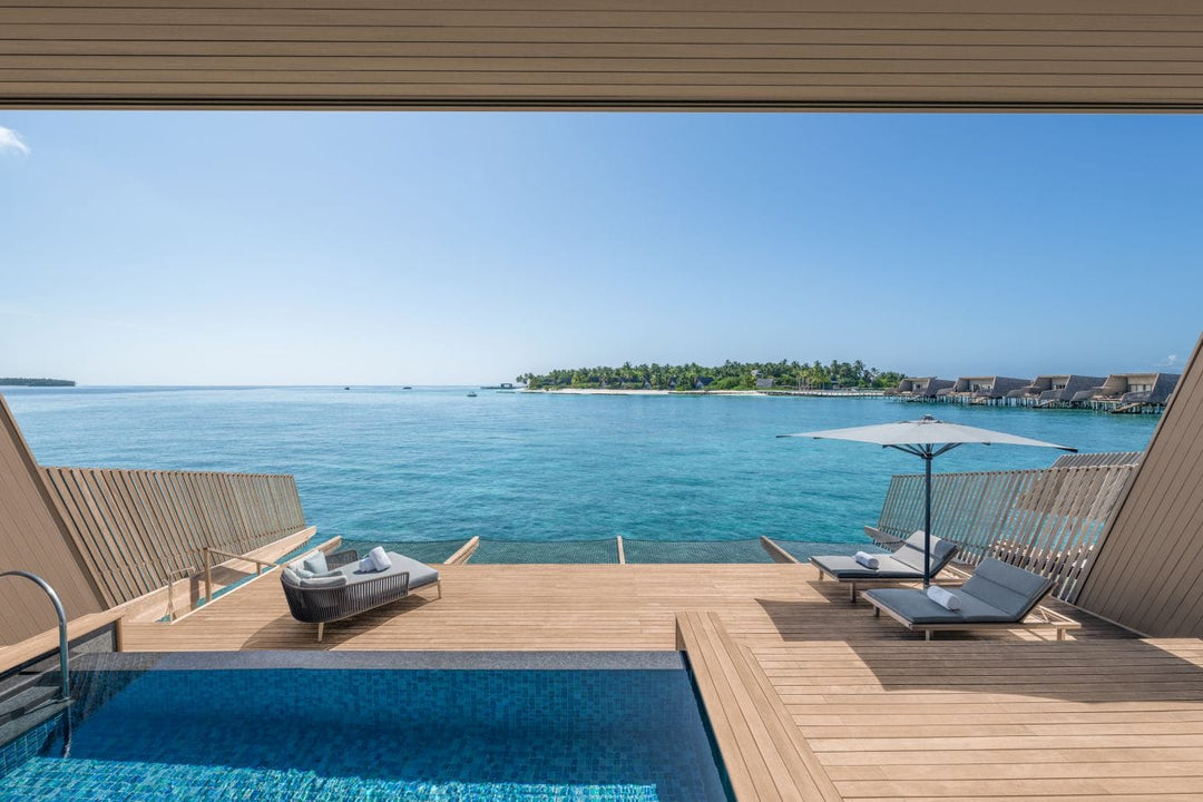 The St. Regis Maldives Vommuli, Dhaalu Atoll — Overwater deck with a pool and two hanging chairs, looking back at the island