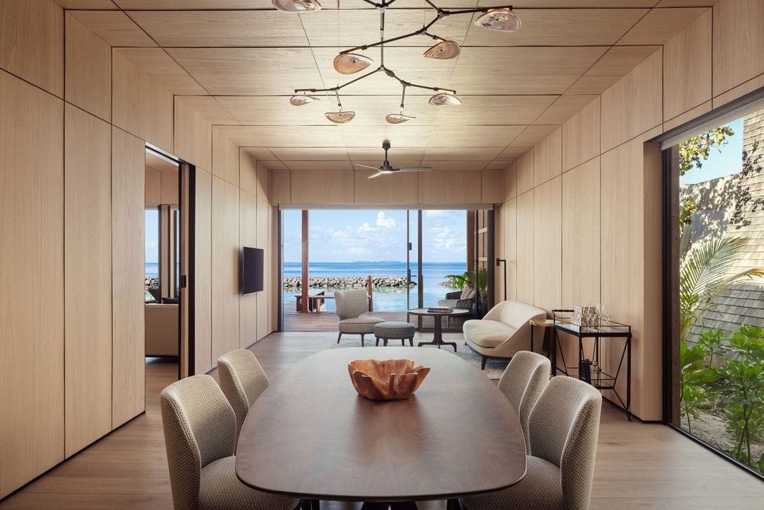 The St. Regis Maldives Vommuli, Dhaalu Atoll — Dining room with an oval table for eight and glass doors onto the deck