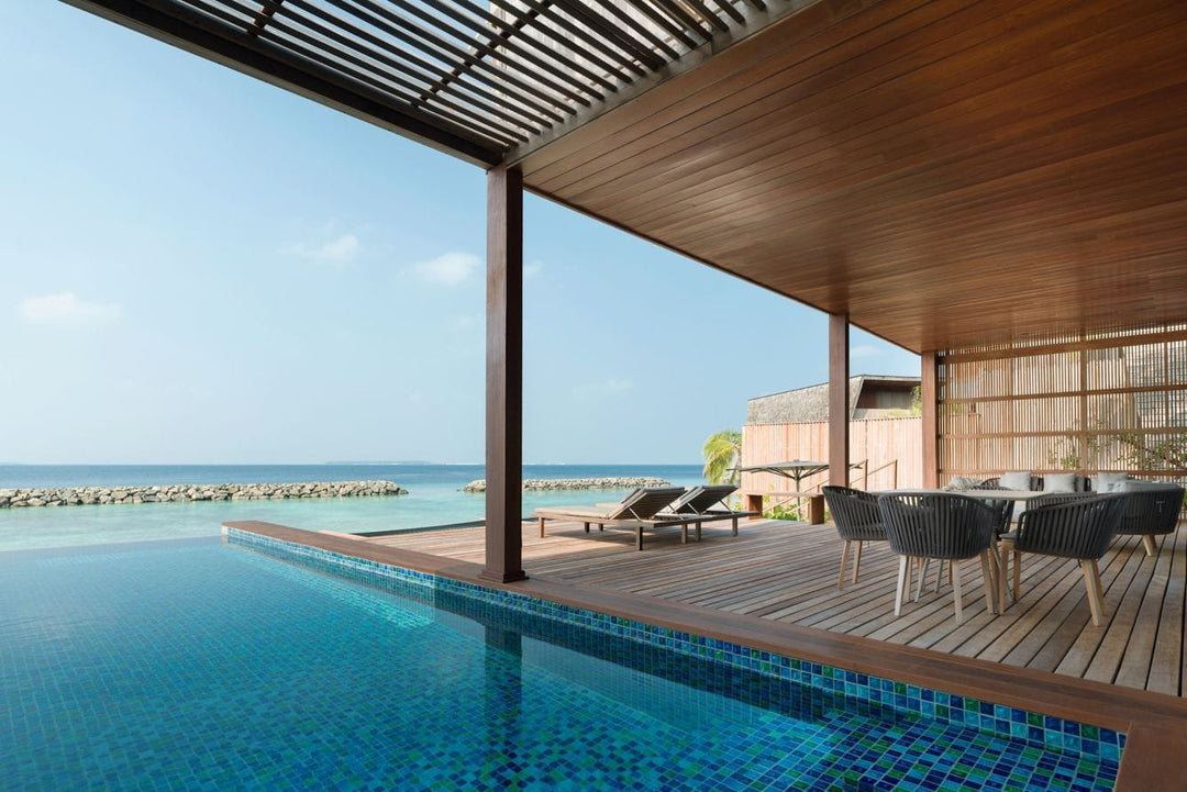 The St. Regis Maldives Vommuli, Dhaalu Atoll — Long pool on a covered deck with a dining table and loungers, the sea beyond