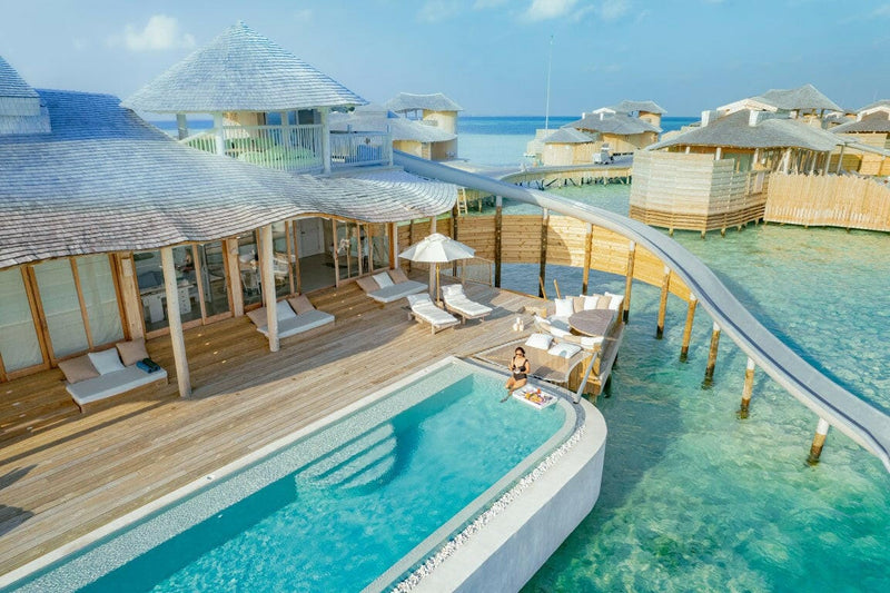 A water villa deck at Soneva Jani, a long pool and shaded loungers ending at the open lagoon.