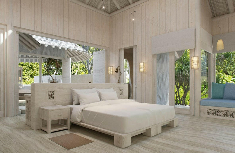 A villa bedroom at Soneva Jani, a white bed and a long low daybed facing doors open to the garden.