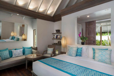 A Beach Villa bedroom at Anantara Dhigu, turquoise cushions on the bed and a sofa along the wall