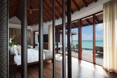 An Over Water Pool Suite bedroom at Anantara Dhigu, wide doors onto the deck and the lagoon