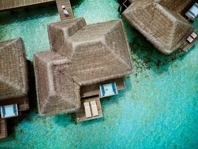 Over water villas at Anantara Veli from directly above, thatched roofs and decks over clear shallow water