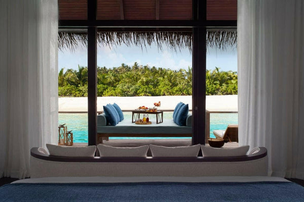 The living area of a Deluxe Over Water Villa at Anantara Veli, a long sofa facing the lagoon